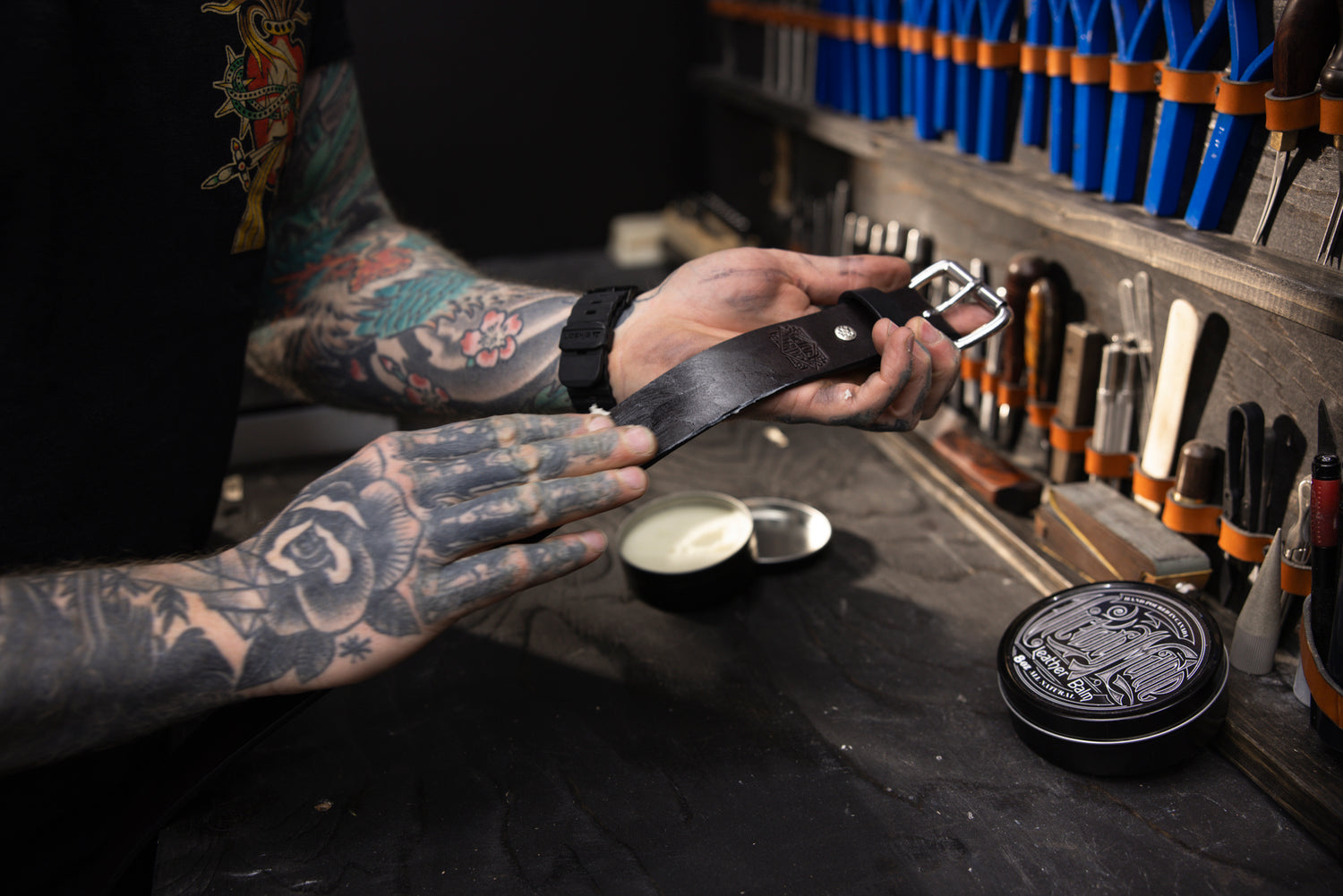 leather craftsman applying leather balm to leather belt